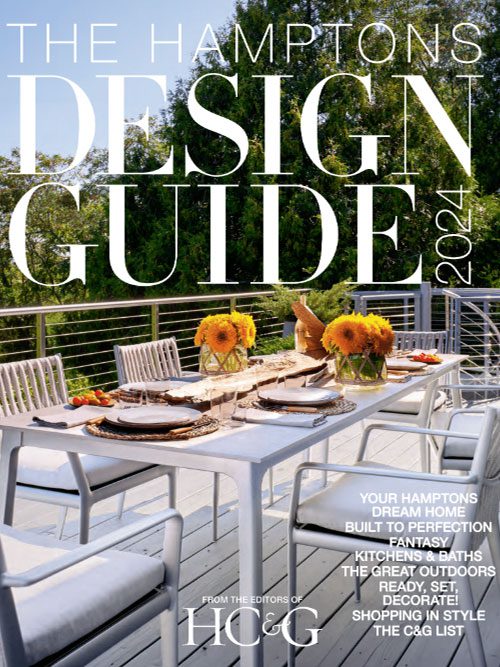 Cover of The Hamptons Design Guide 2024 featuring an outdoor dining setup on a deck with white furniture and floral centerpieces, surrounded by greenery.