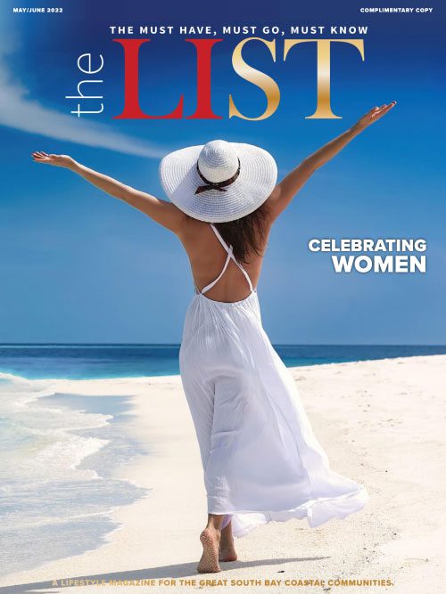 Woman in a white dress and hat walking on a beach with arms outstretched, featured on the cover of "The List" magazine.